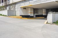 an empty parking garage with a yellow curb and some signs above the door and side of a building