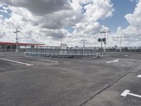 an empty parking lot on a cloudy day with parking meters and street lights on either side