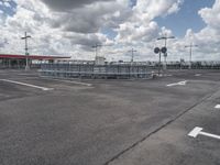 an empty parking lot on a cloudy day with parking meters and street lights on either side