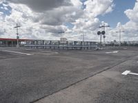 an empty parking lot on a cloudy day with parking meters and street lights on either side