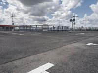 an empty parking lot on a cloudy day with parking meters and street lights on either side