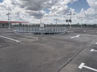 an empty parking lot on a cloudy day with parking meters and street lights on either side