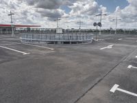 an empty parking lot on a cloudy day with parking meters and street lights on either side