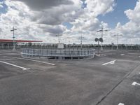 an empty parking lot on a cloudy day with parking meters and street lights on either side