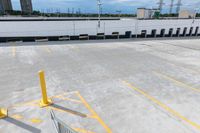 a parking lot with white walls, cars parked and yellow barriers in the middle of the parking lot