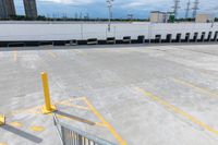 a parking lot with white walls, cars parked and yellow barriers in the middle of the parking lot