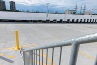 a parking lot with white walls, cars parked and yellow barriers in the middle of the parking lot