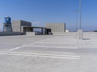 a large parking lot has two buildings and an air tower in the background on a sunny day