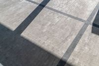 the shadow of an umbrella is on a tiled floor with a window and light coming in from a small window