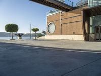 a skateboarder is going down the street beside the water and some buildings and people are out on a sunny day