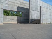 the empty parking lot in front of a wall with apartment buildings on it and a skateboarder on a ramp