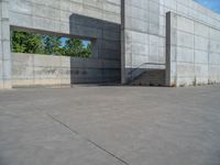 the empty parking lot in front of a wall with apartment buildings on it and a skateboarder on a ramp