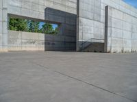 the empty parking lot in front of a wall with apartment buildings on it and a skateboarder on a ramp