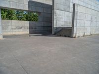 the empty parking lot in front of a wall with apartment buildings on it and a skateboarder on a ramp