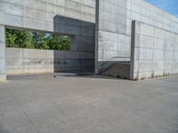 the empty parking lot in front of a wall with apartment buildings on it and a skateboarder on a ramp