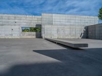 the empty parking lot in front of a wall with apartment buildings on it and a skateboarder on a ramp