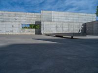 the empty parking lot in front of a wall with apartment buildings on it and a skateboarder on a ramp