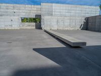 the empty parking lot in front of a wall with apartment buildings on it and a skateboarder on a ramp