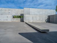 the empty parking lot in front of a wall with apartment buildings on it and a skateboarder on a ramp