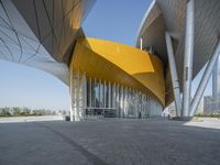 the exterior of a modern architecture building with curved walls and arches that are painted yellow