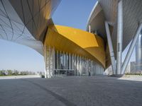 the exterior of a modern architecture building with curved walls and arches that are painted yellow