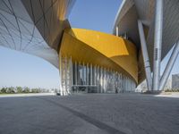 the exterior of a modern architecture building with curved walls and arches that are painted yellow