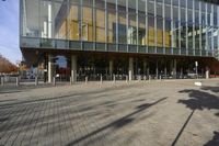 a modern building with lots of glass on the outside and inside of it, with a pedestrian pathway outside