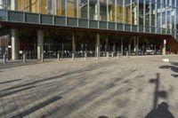 a modern building with lots of glass on the outside and inside of it, with a pedestrian pathway outside