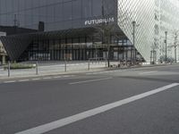 two people riding bikes outside a black building on the street with windows that say futuria,