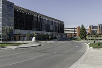 the large building on the corner of an empty lot with trees and shrubs around it