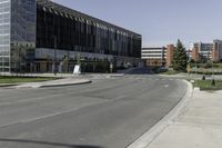 the large building on the corner of an empty lot with trees and shrubs around it