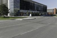 the large building on the corner of an empty lot with trees and shrubs around it