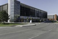 the large building on the corner of an empty lot with trees and shrubs around it