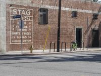 a green bicycle sits parked by the side of a building on a road with bicycles parked in front