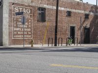 a green bicycle sits parked by the side of a building on a road with bicycles parked in front