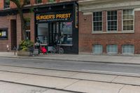 a bicycle parked on a trolley track in front of a burger's finest store