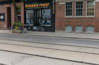 a bicycle parked on a trolley track in front of a burger's finest store