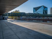 a skateboarder riding on a cement ramp next to a city street under a bridge