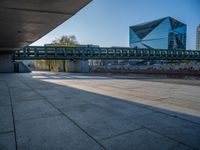 a skateboarder riding on a cement ramp next to a city street under a bridge