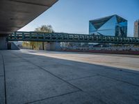 a skateboarder riding on a cement ramp next to a city street under a bridge