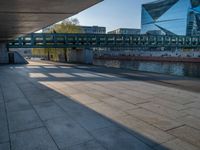 a skateboarder riding on a cement ramp next to a city street under a bridge