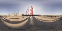 some people are walking by a roller coaster and many trees and bushes in the middle of the image