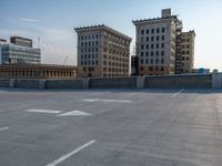 several large empty parking spaces in the city with buildings nearby in front of them -