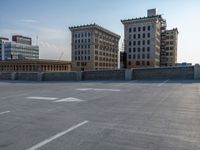 several large empty parking spaces in the city with buildings nearby in front of them -