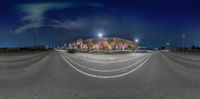 a fish eye view of a road at night with street lights and building in the background