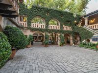 there is a courtyard with many plants and plants around it at the front of the house