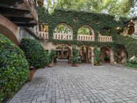 there is a courtyard with many plants and plants around it at the front of the house