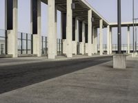 an empty sidewalk that has some columns in it under a blue sky with clouds on the top