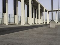 an empty sidewalk that has some columns in it under a blue sky with clouds on the top