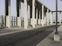 an empty sidewalk that has some columns in it under a blue sky with clouds on the top